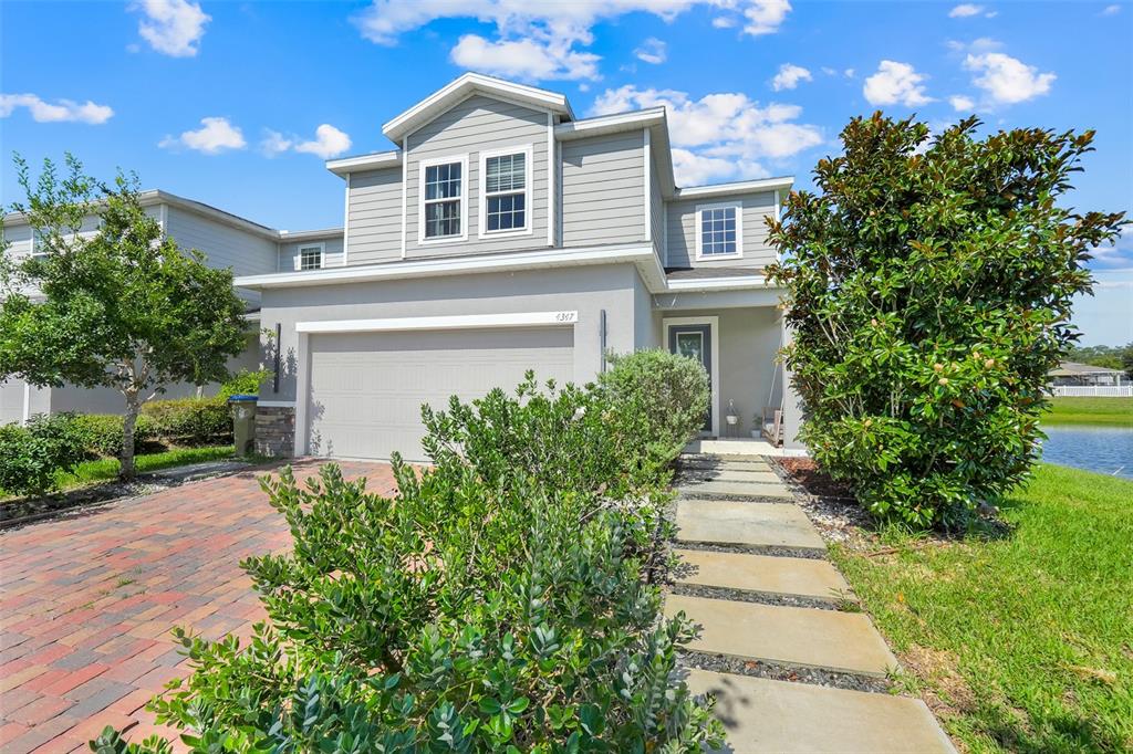 A two-story house with a brick driveway, gray siding, and a stone-paved walkway — 4347 SILVER CREEK STREET, KISSIMMEE, FL
