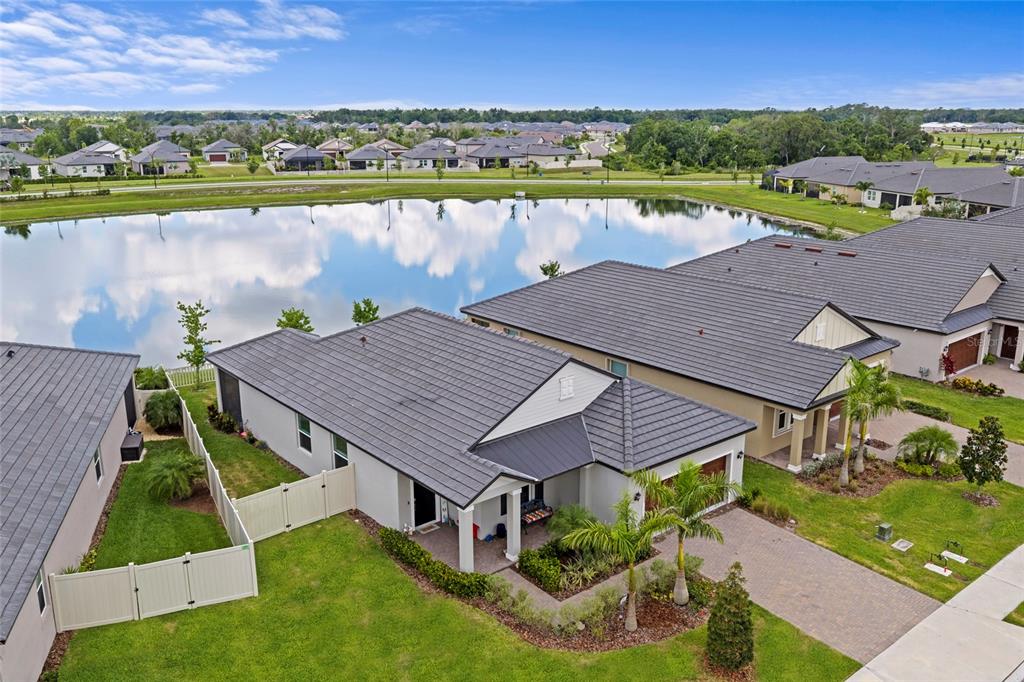 An aerial view shows a suburban house with a tile roof, fenced yard, and pond — 12657 TAHITIAN PEARL CIRCLE, PARRISH, FL