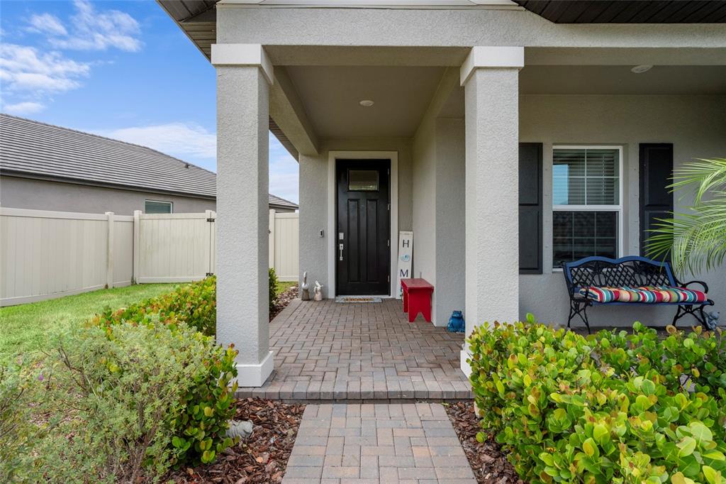 A covered entryway features a black front door, brick pavers, and a metal bench — 12657 TAHITIAN PEARL CIRCLE, PARRISH, FL