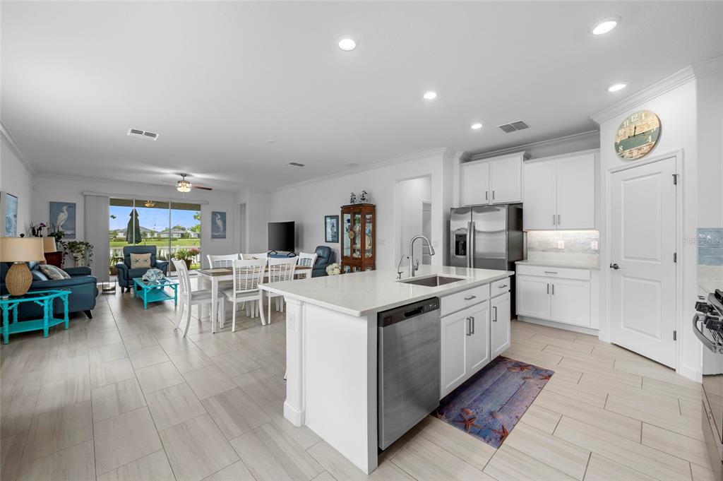 An open-concept kitchen with white cabinets and a center island overlooks a dining area — 12657 TAHITIAN PEARL CIRCLE, PARRISH, FL