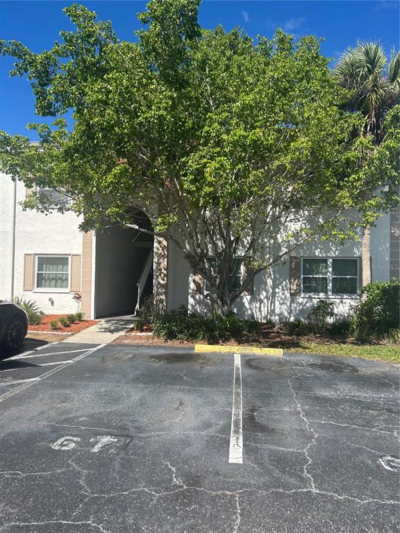 A two-story apartment building exterior features a large tree and a numbered parking space — 383 S MCMULLEN BOOTH ROAD UNIT 68, CLEARWATER, FL