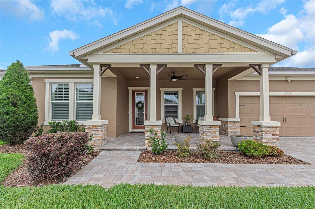 A single-story house with a covered front porch, stone pillars, and a paved walkway — 4239 WOODLAND RETREAT BOULEVARD, NEW PORT RICHEY, FL