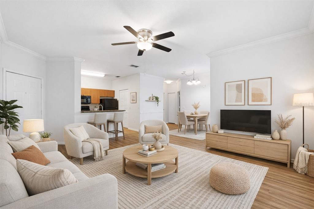 A living room with light wood floors, a neutral sofa, two armchairs, and a television — 2171 PORTOFINO PLACE UNIT 7-2723, PALM HARBOR, FL