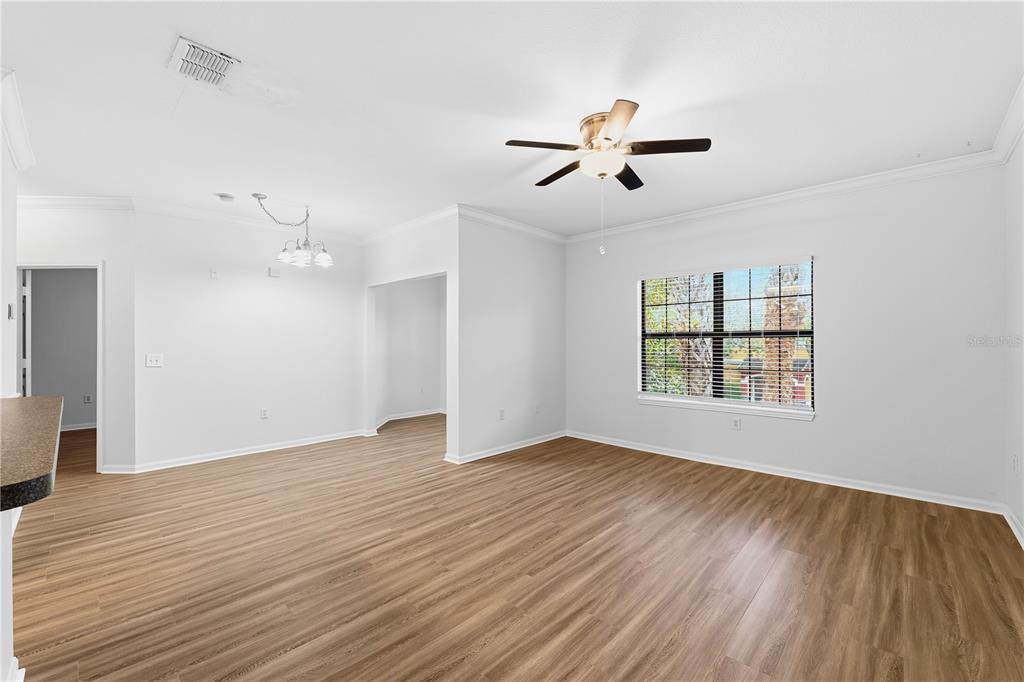 An empty living room with light wood-look flooring, a ceiling fan, and a large window — 2171 PORTOFINO PLACE UNIT 7-2723, PALM HARBOR, FL