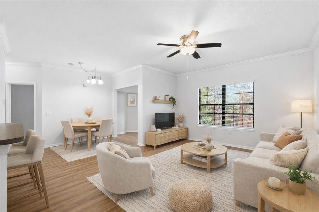 An open-concept living and dining area features light wood flooring, neutral furniture, and a ceiling fan — 2171 PORTOFINO PLACE UNIT 7-2723, PALM HARBOR, FL