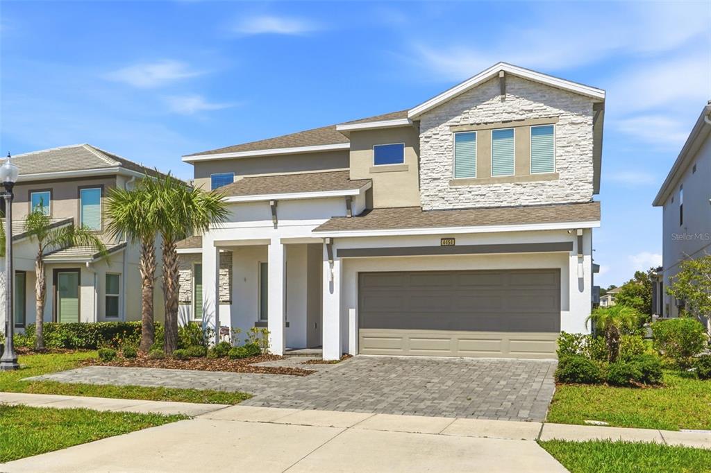 A two-story suburban house with a stone facade, white trim, and a two-car garage — 4454 MONADO DRIVE, KISSIMMEE, FL