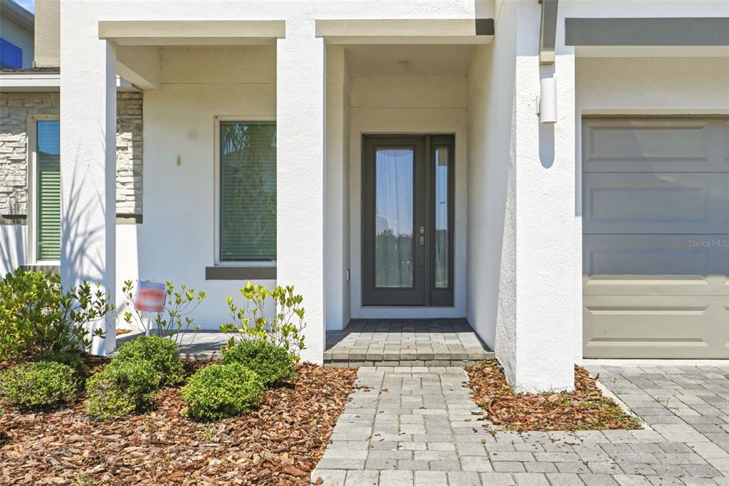 A front exterior view showing a paved walkway leading to a glass-paneled front door — 4454 MONADO DRIVE, KISSIMMEE, FL