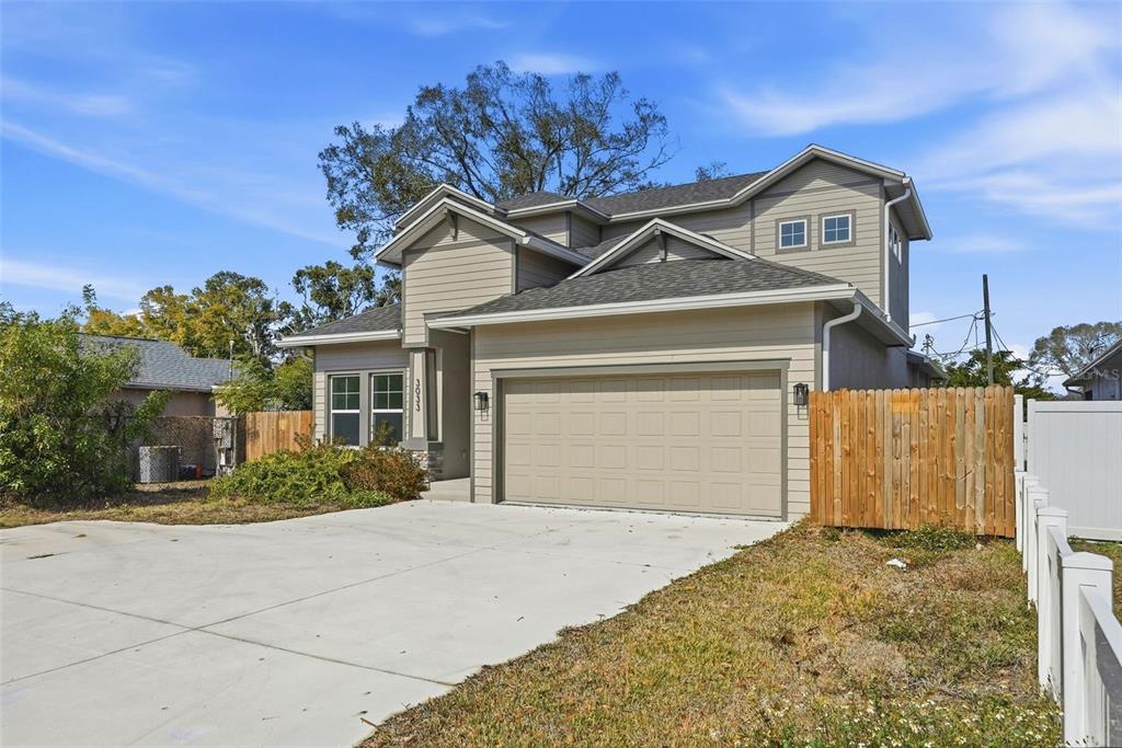 A two-story house with tan siding, a two-car garage, and a wooden fence — 3033 54TH AVENUE N, ST PETERSBURG, FL