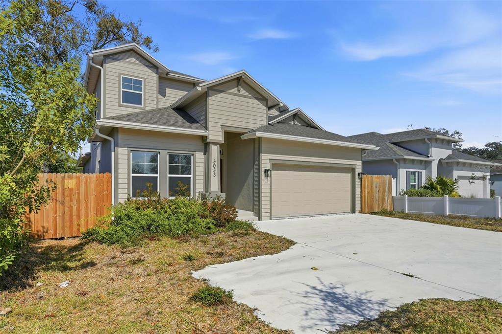 A two-story suburban house with beige siding, a two-car garage, and a concrete driveway — 3033 54TH AVENUE N, ST PETERSBURG, FL