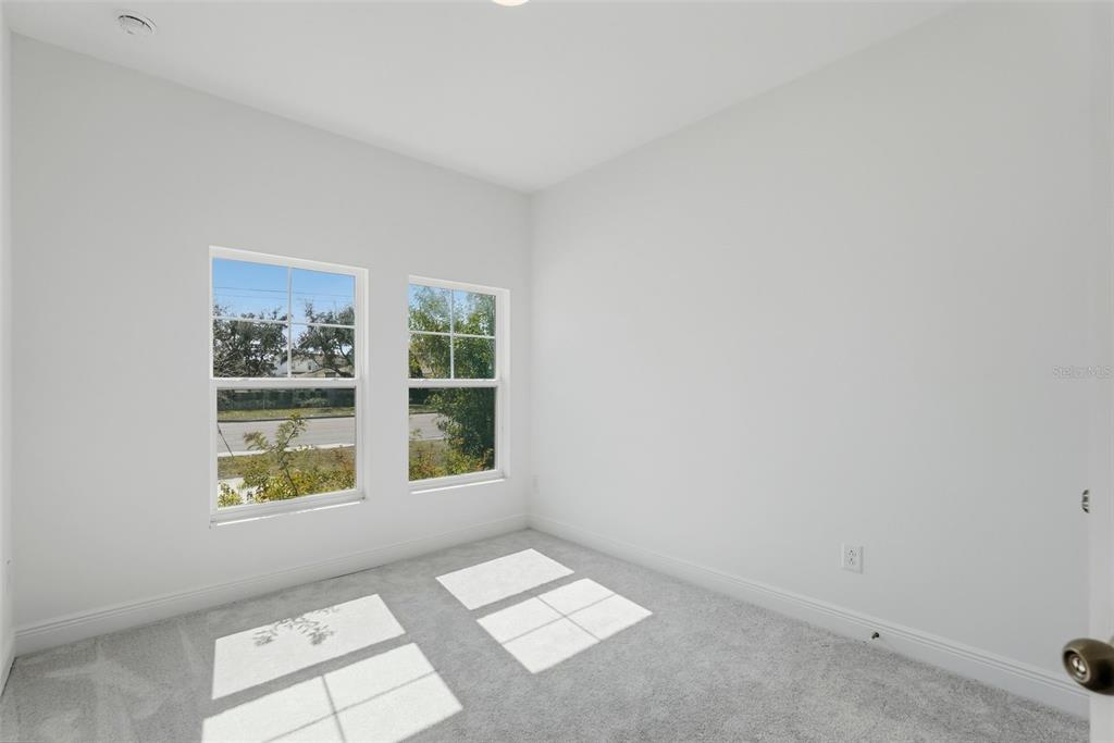 An empty bedroom with white walls, gray carpet, and two windows overlooking a street — 3033 54TH AVENUE N, ST PETERSBURG, FL