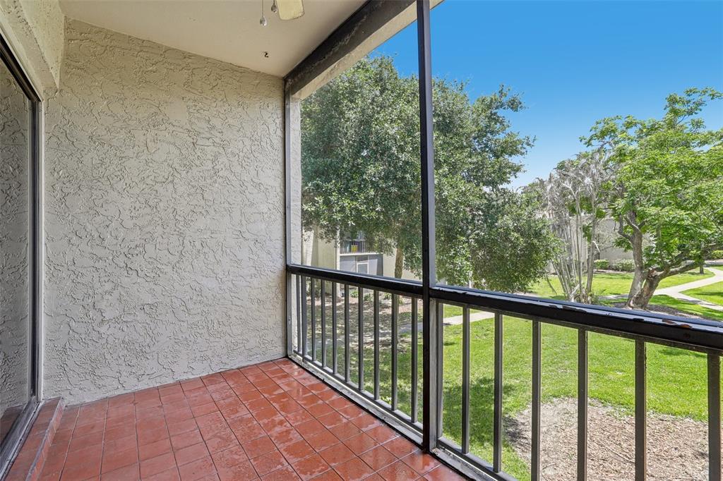 A screened-in balcony features red tile flooring, a textured stucco wall, and a metal railing — 3252 S SEMORAN BOULEVARD UNIT 22, ORLANDO, FL