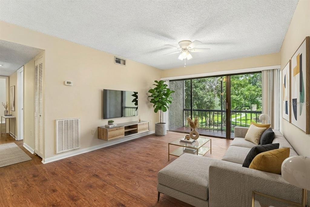 A living room features a sectional sofa, wall-mounted television, floating console, and sliding glass doors — 3252 S SEMORAN BOULEVARD UNIT 22, ORLANDO, FL