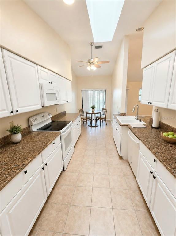 A galley kitchen features white cabinets, granite countertops, and a dining area with a ceiling fan — 1203 SAXONY CIRCLE UNIT C, PUNTA GORDA, FL