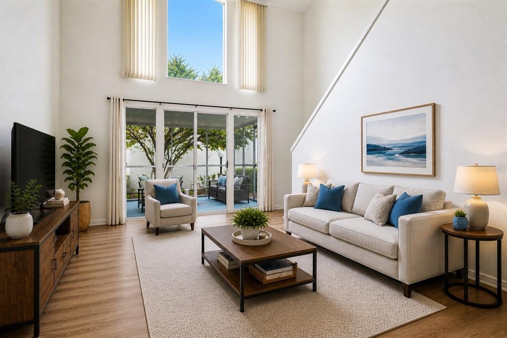 A bright living room features high ceilings, a sofa, a coffee table, and sliding glass doors — 500 ORANGE DRIVE UNIT 10, ALTAMONTE SPRINGS, FL