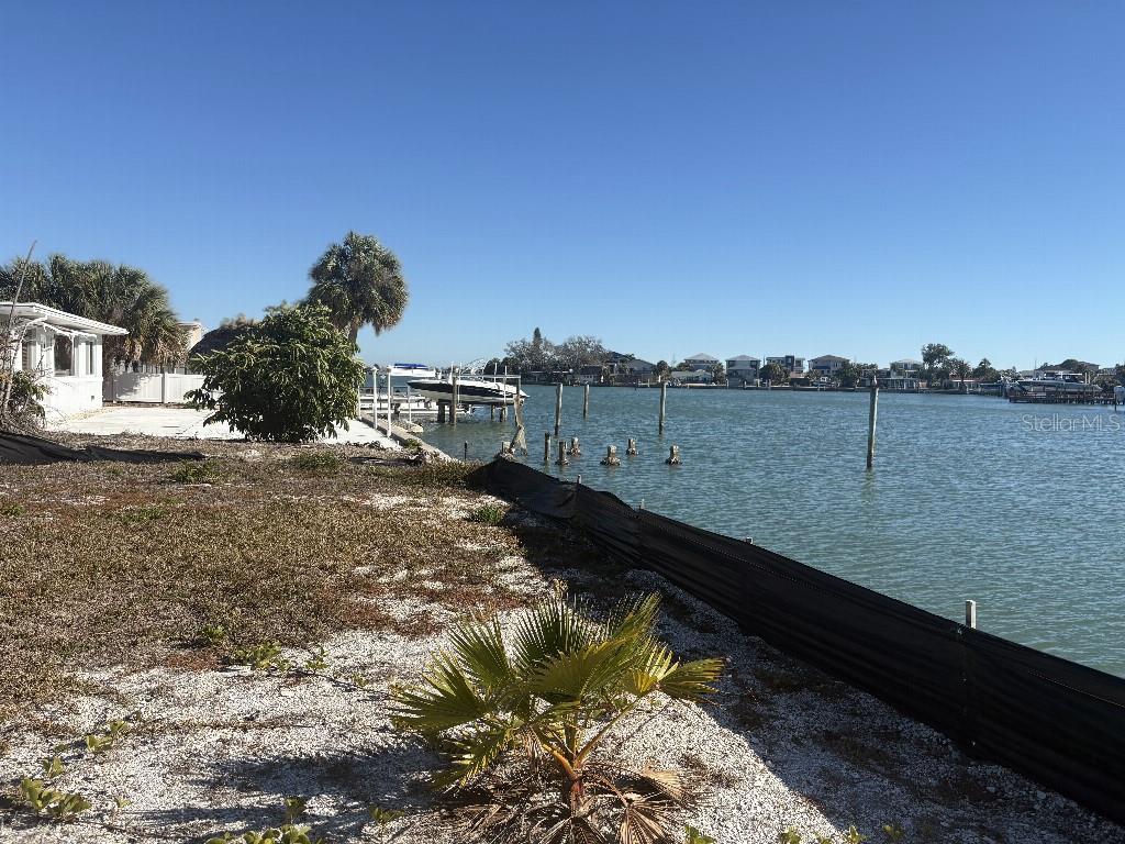 A waterfront property features a sandy yard, a silt fence, and a boat lift — 5410 ALOHA DRIVE, ST PETE BEACH, FL