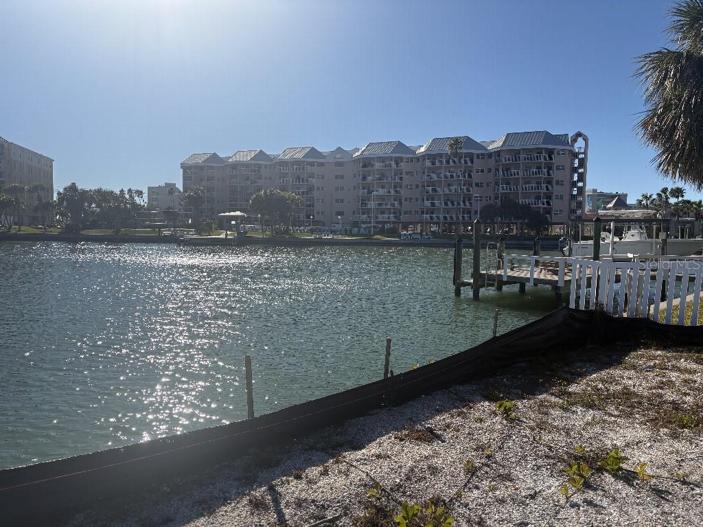 A view of a multi-story waterfront condominium building across a canal with a boat dock — 5410 ALOHA DRIVE, ST PETE BEACH, FL