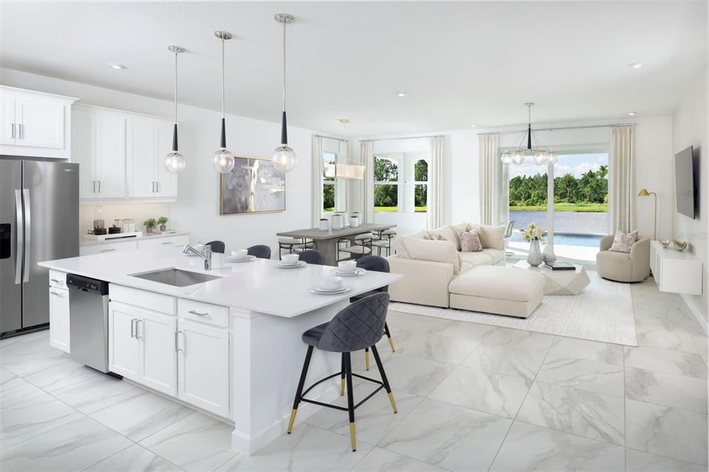 A bright open-concept kitchen and living area with white cabinetry, a large island, and lake views — 11801 SEALIGHT STREET, VENICE, FL