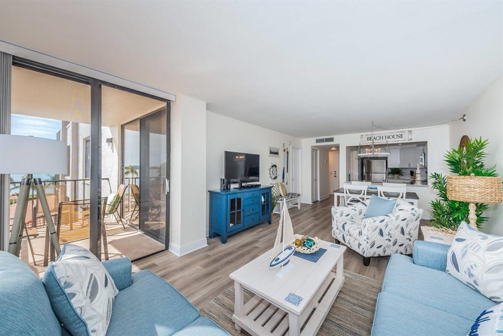 A living room with blue furniture, a white coffee table, and a balcony overlooking water — 6357 BAHIA DEL MAR BOULEVARD UNIT 407, ST PETERSBURG, FL