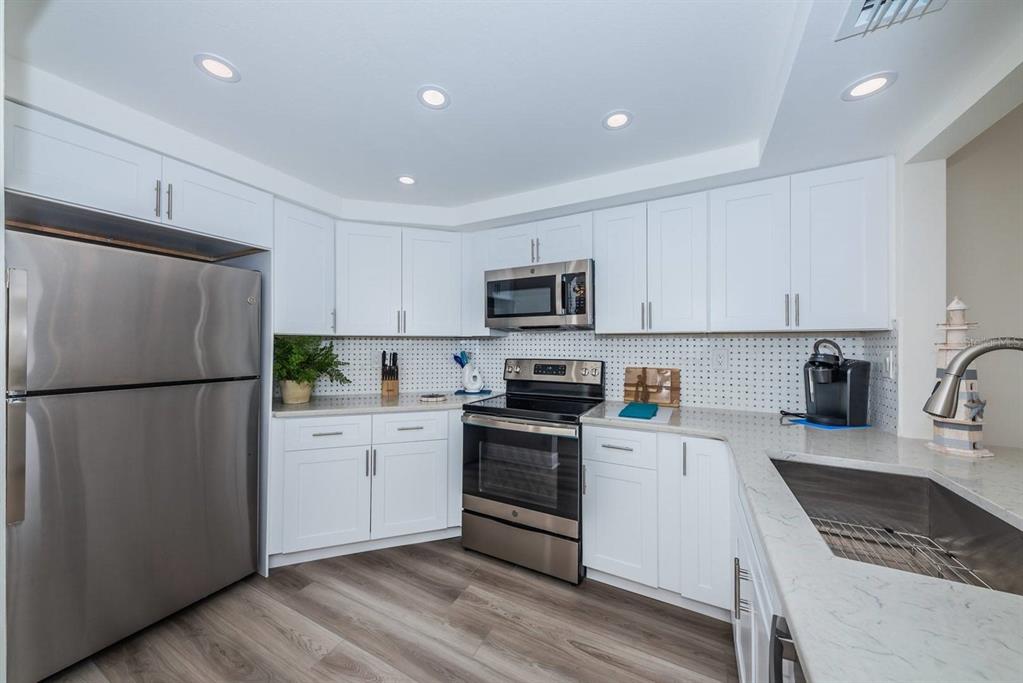 A kitchen with white cabinets, stainless steel appliances, and a light-colored countertop — 6357 BAHIA DEL MAR BOULEVARD UNIT 407, ST PETERSBURG, FL