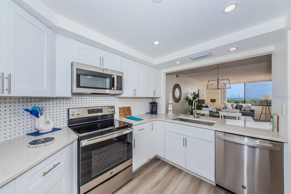 A kitchen with white cabinets, stainless steel appliances, and a view into the living area — 6357 BAHIA DEL MAR BOULEVARD UNIT 407, ST PETERSBURG, FL
