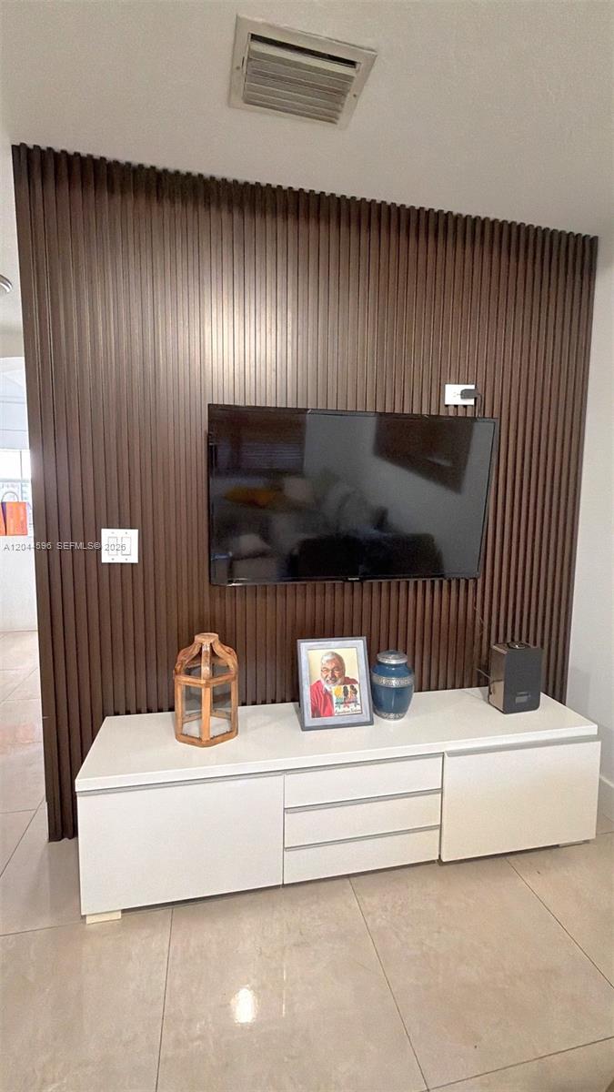 A wall-mounted television is centered on a dark wood-slatted accent wall above a white console — 11405 NW 62nd Ter # 236, Doral FL 33178, DORAL, FL