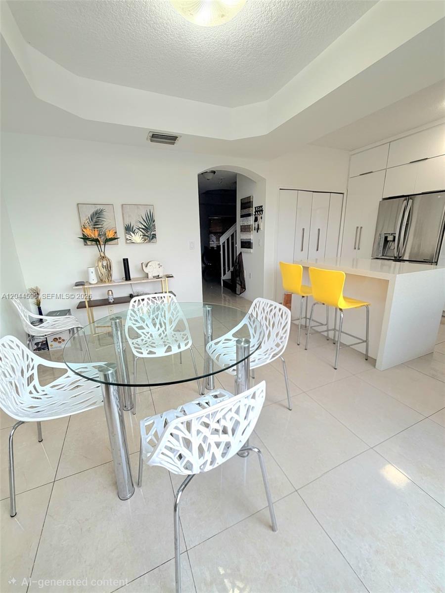 A dining area with a glass table, white chairs, and a kitchen island with yellow stools — 11405 NW 62nd Ter # 236, Doral FL 33178, DORAL, FL
