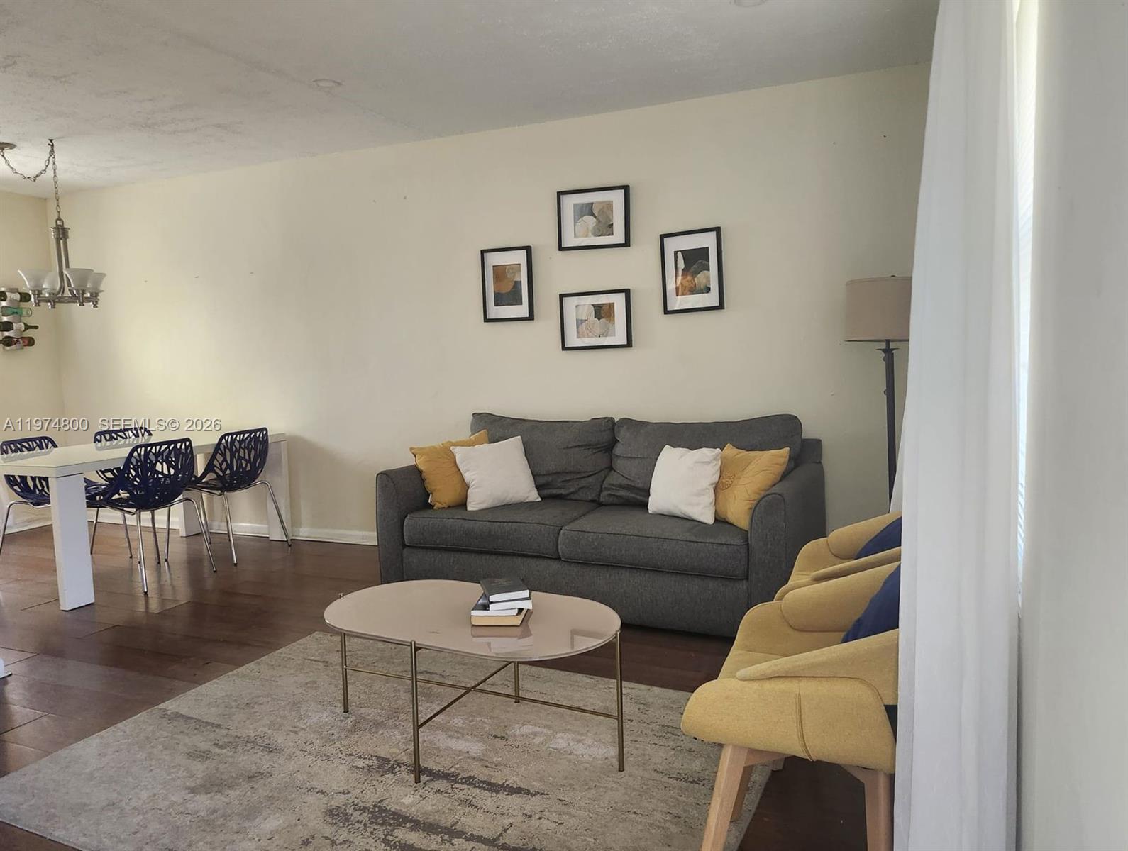 A living room features a gray sofa, yellow armchairs, a coffee table, and a dining area — 11220 NE 11th Pl # 11220, Biscayne Park FL 33161, BISCAYNE PARK, FL