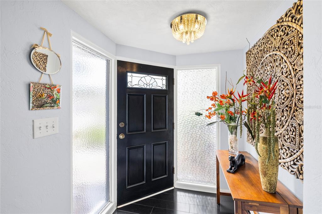A paved walkway leads to the front entrance of a white house with black trim — 14006 81ST AVENUE, SEMINOLE, FL