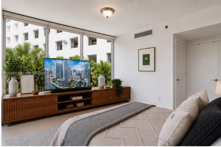 A bedroom features a wooden media console, a television, and large windows overlooking lush greenery — 495 Brickell Ave # 411, Miami FL 33131, MIAMI, FL