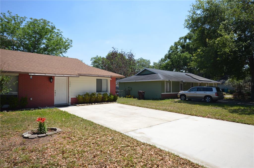 A single-story house with a red brick facade and a concrete driveway sits outdoors — 1397 CANDLEWYCK DRIVE, ORLANDO, FL