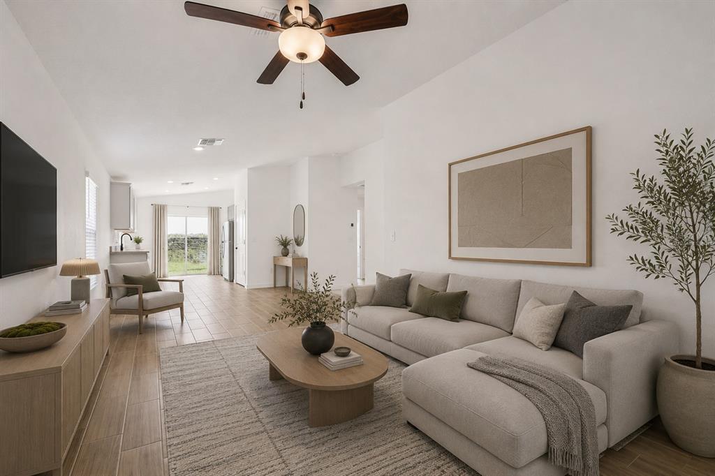A bright living room features a sectional sofa, wood-look tile floors, and a ceiling fan — 602 BLACKTHORN DRIVE, LAKELAND, FL