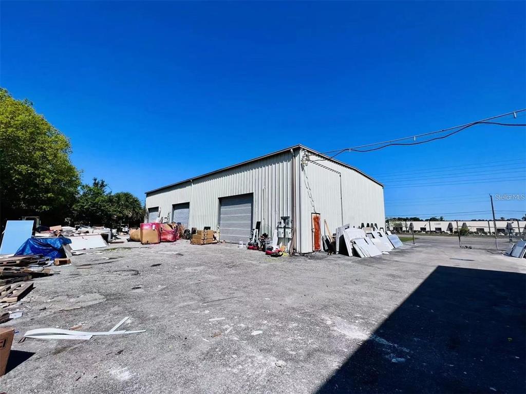 A metal-sided industrial warehouse building sits on a gravel lot under a clear blue sky — 2398 63RD AVENUE E, BRADENTON, FL