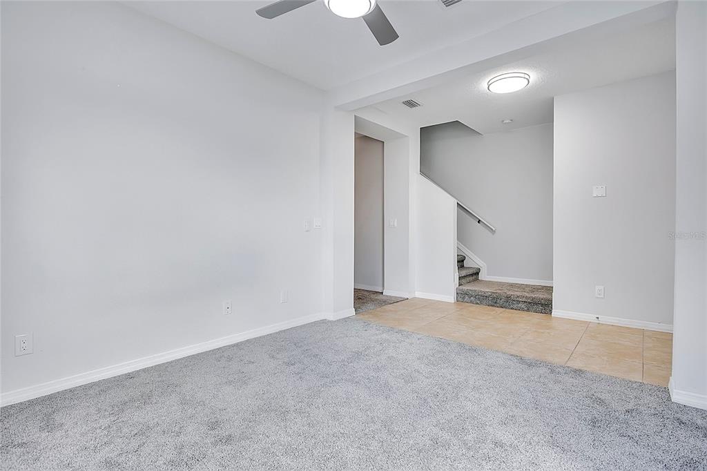 A living area features gray carpeting, tiled flooring near the stairs, and a ceiling fan — 427 IRONSIDE TRAIL DRIVE, GROVELAND, FL