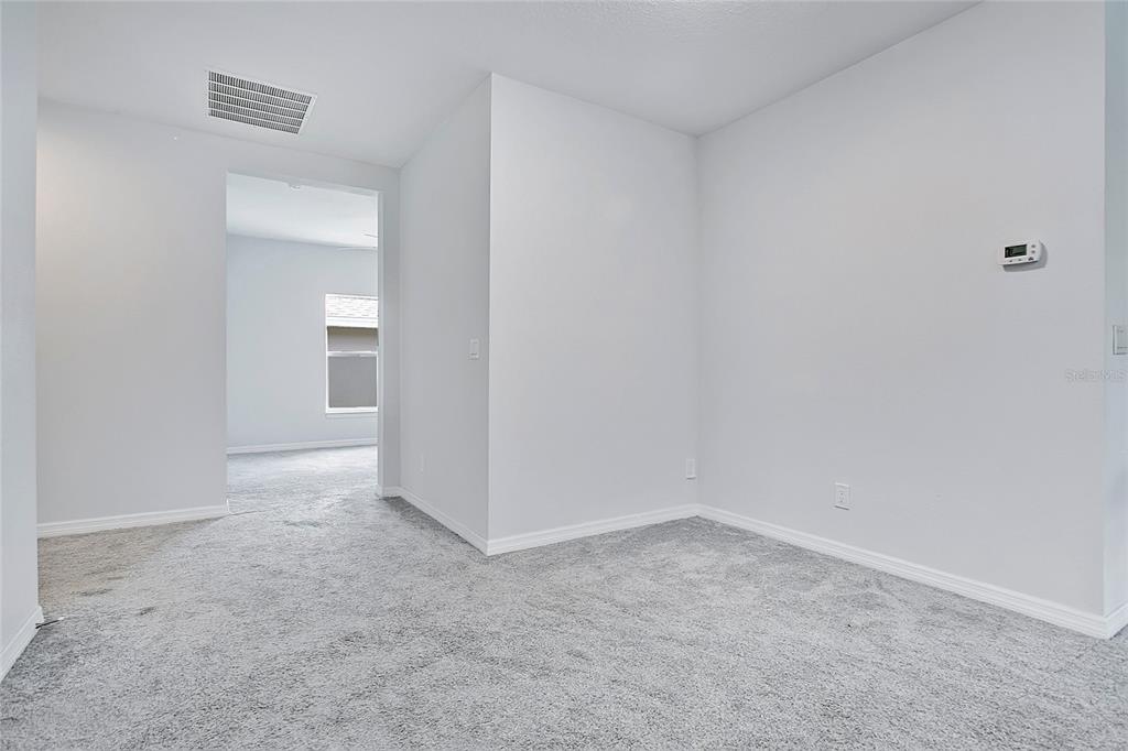 A carpeted room with light gray walls leads to an adjacent room through a doorway — 427 IRONSIDE TRAIL DRIVE, GROVELAND, FL