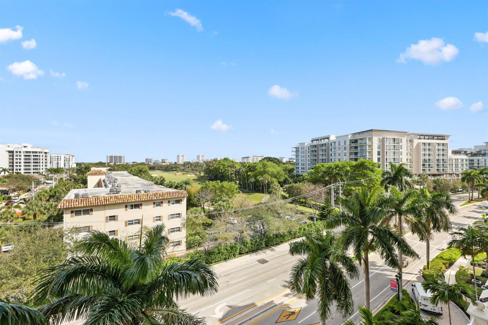 An elevated view shows a street, palm trees, a low-rise building, and distant apartment complexes — 99 SE Mizner Boulevard # 609, Boca Raton FL 33432, BOCA RATON, FL