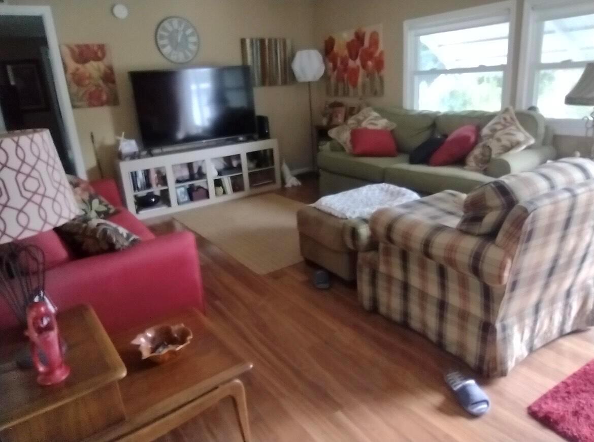 A living room features a television on a white media console, a sofa, and chairs — 13827 S Indian River Drive # 5, Jensen Beach FL 34957, JENSEN BEACH, FL