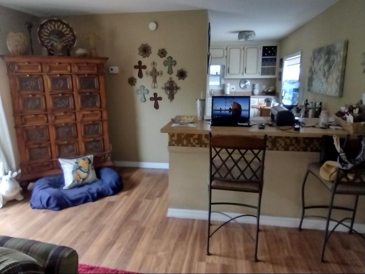 A living room with a wooden cabinet, a pet bed, and a kitchen breakfast bar — 13827 S Indian River Drive # 5, Jensen Beach FL 34957, JENSEN BEACH, FL