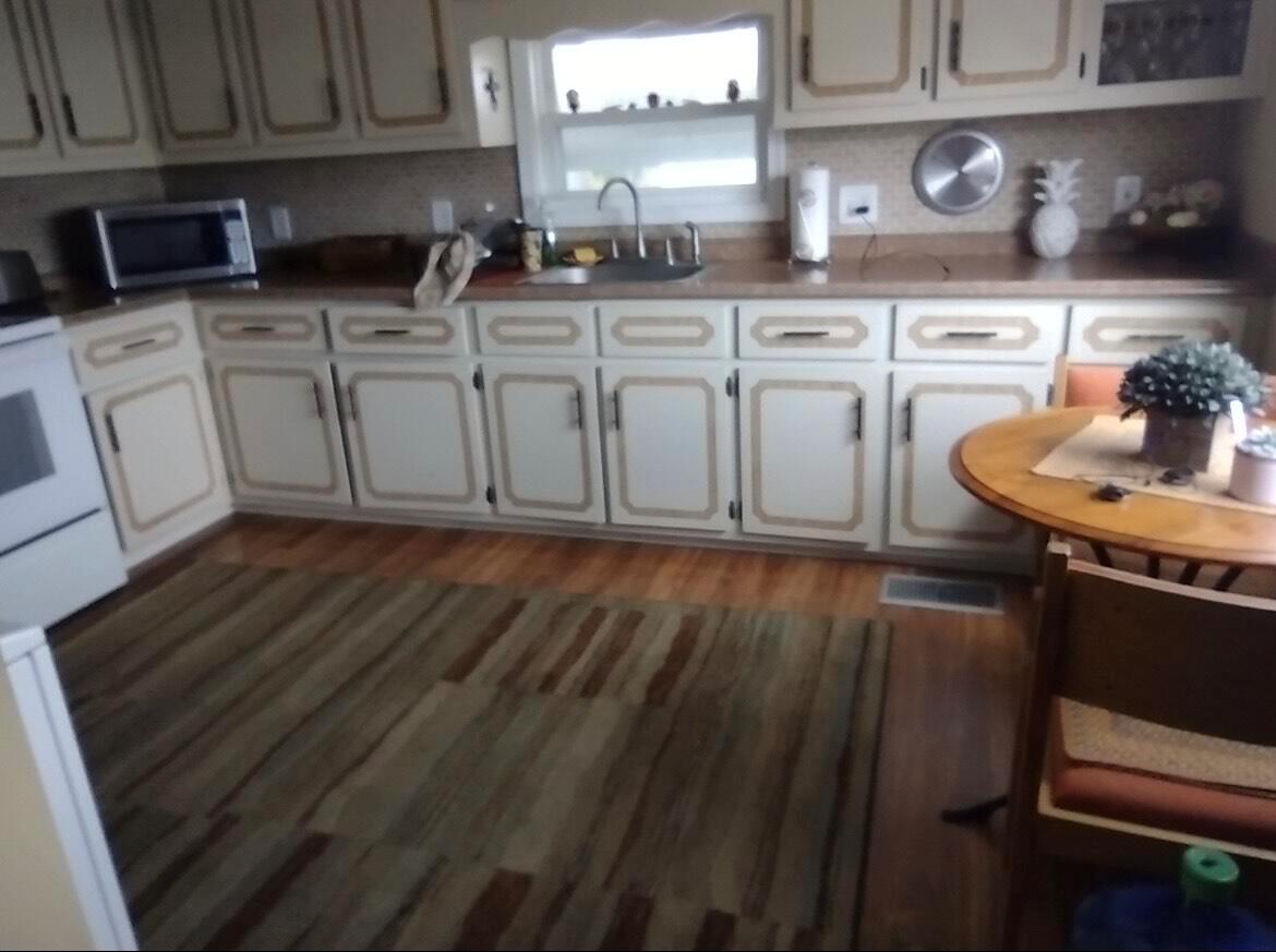 A kitchen features light-colored cabinets with dark trim, wood-look flooring, and a small dining table — 13827 S Indian River Drive # 5, Jensen Beach FL 34957, JENSEN BEACH, FL
