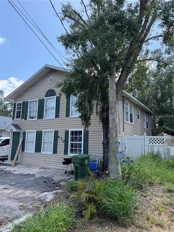 A two-story house with beige siding, green shutters, and a large tree in the yard — 610 21ST STREET W, BRADENTON, FL