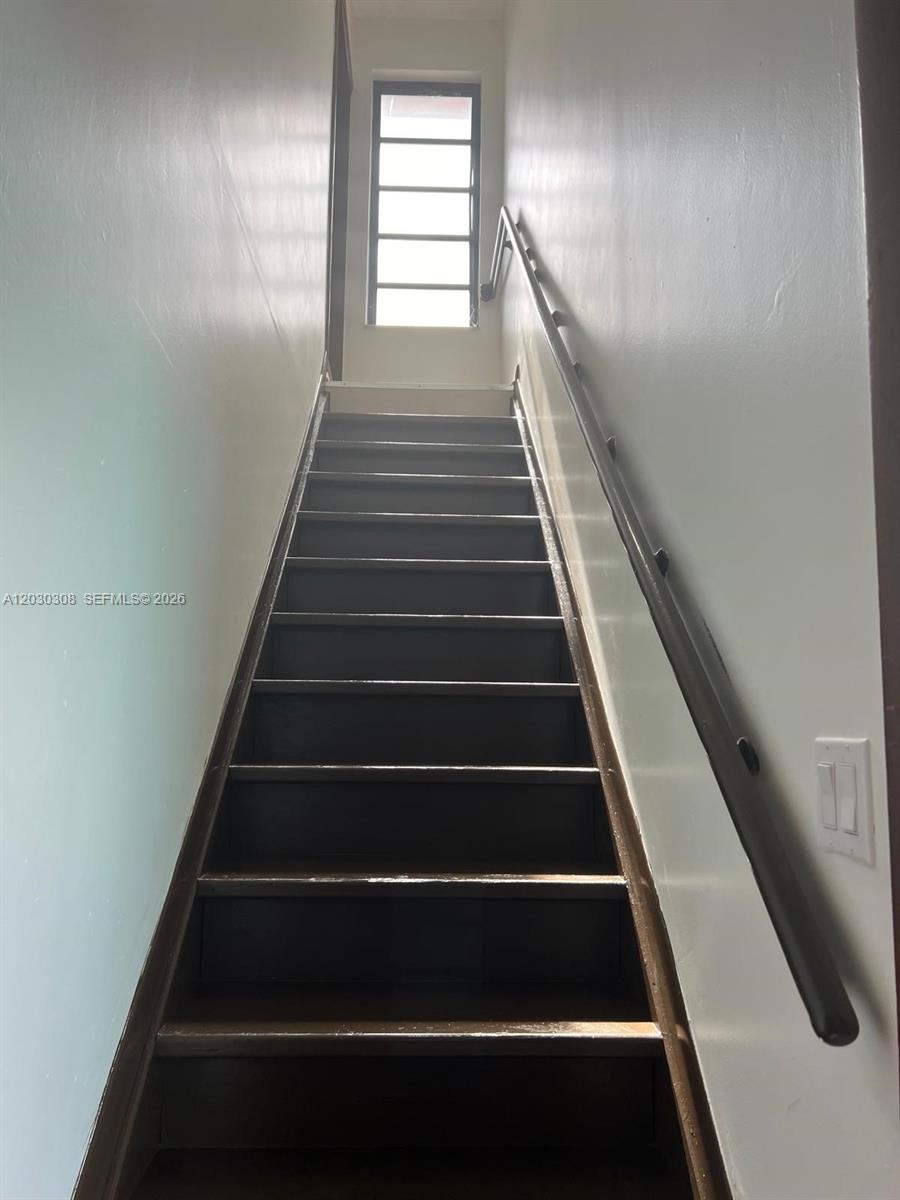 A straight wooden staircase with a handrail leads up to a window — 321 SW 71st Ave # 2, Miami FL 33144, MIAMI, FL