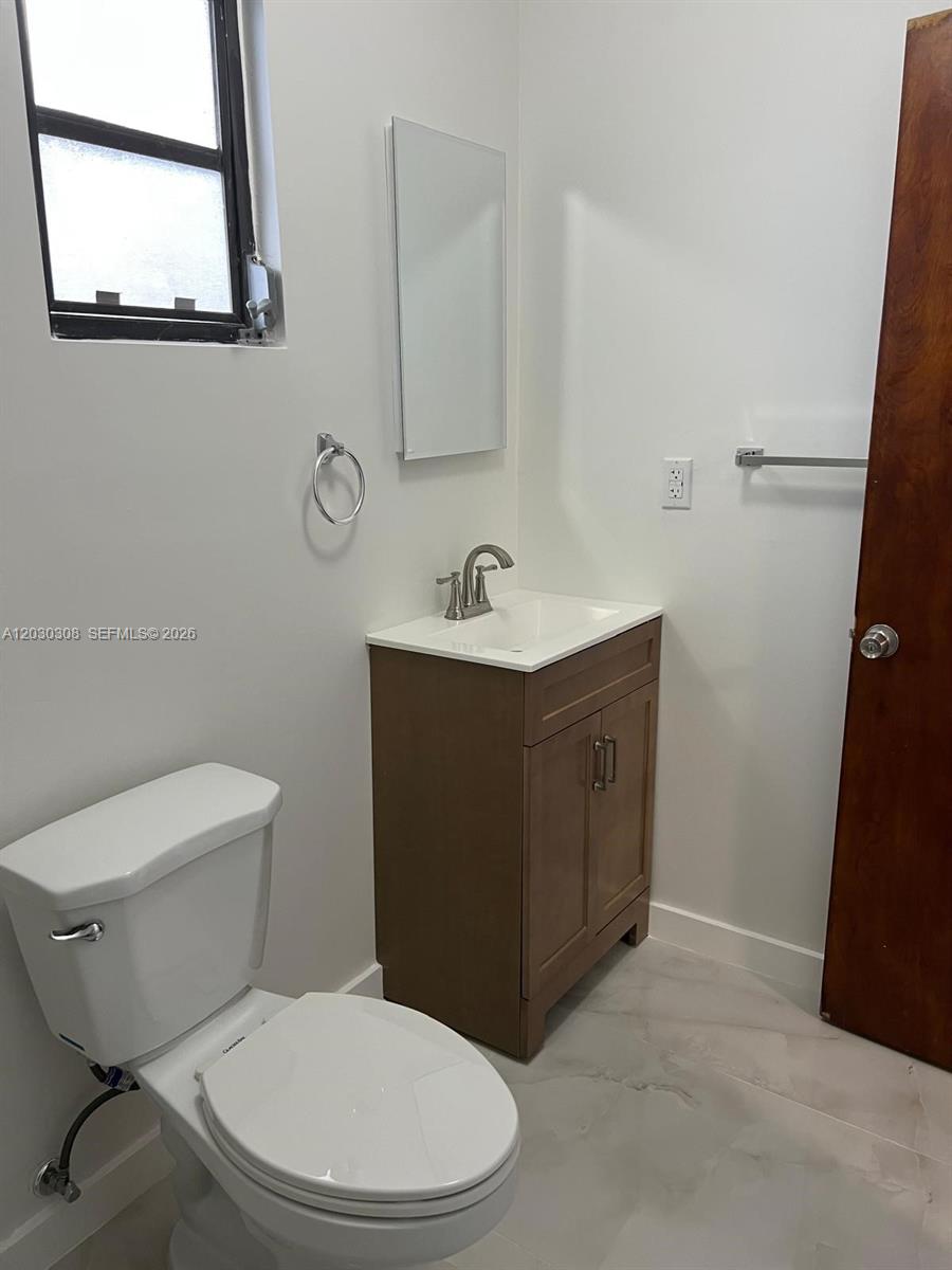 A small bathroom features a white toilet, a wood vanity with a sink, and tile flooring — 321 SW 71st Ave # 2, Miami FL 33144, MIAMI, FL