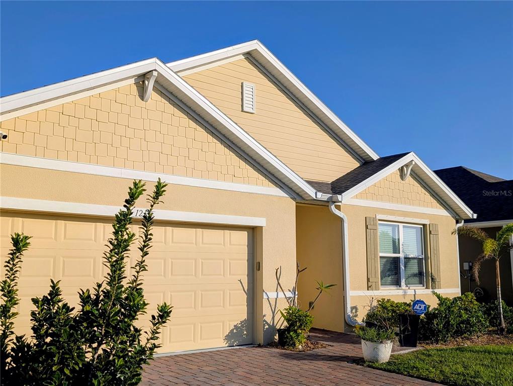 A tan single-story house with a two-car garage and a brick paver driveway — 1215 DUGAN CIRCLE SE, PALM BAY, FL