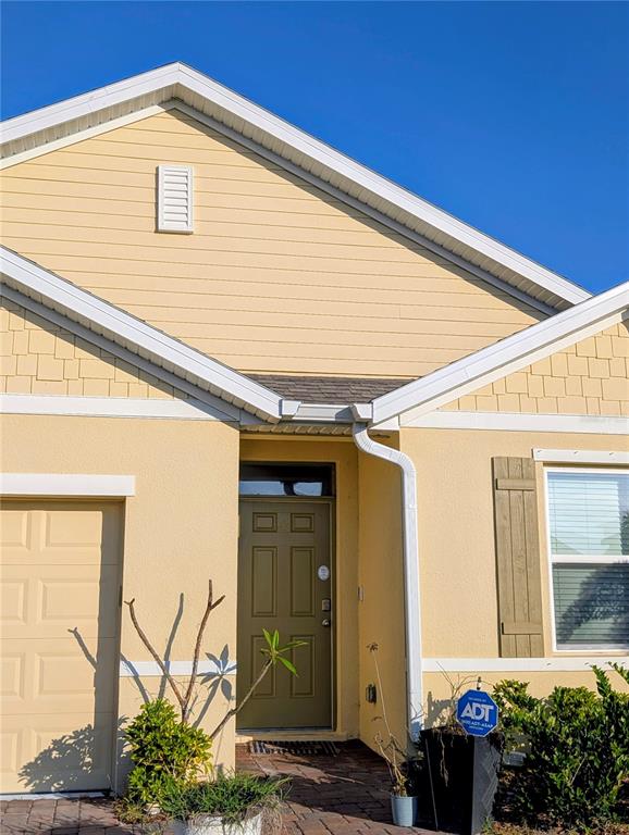 The exterior of a yellow house features a front door, a garage, and a window — 1215 DUGAN CIRCLE SE, PALM BAY, FL