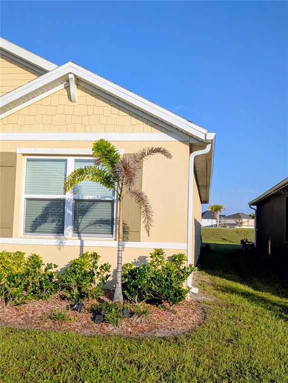 A yellow house exterior features a palm tree in the front garden bed — 1215 DUGAN CIRCLE SE, PALM BAY, FL