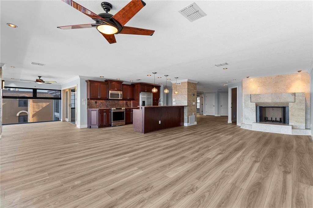 An open-concept living area features wood-look flooring, a dark wood kitchen, and a stone fireplace — 1600 W MARION AVENUE UNIT 234, PUNTA GORDA, FL