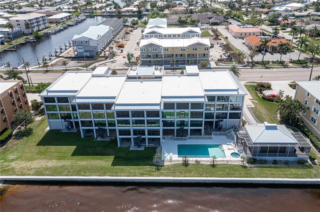 An aerial view shows a multi-story building with a swimming pool and a canal — 1600 W MARION AVENUE UNIT 234, PUNTA GORDA, FL