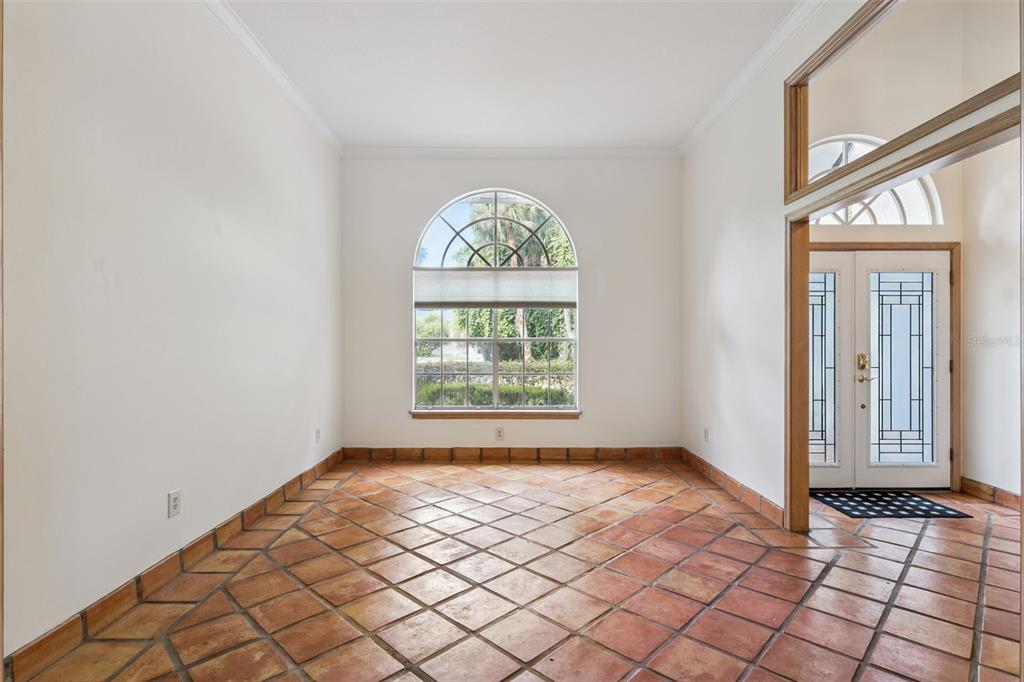 An empty room with terracotta tile flooring, white walls, and a large arched window — 381 CREEKSTONE COURT, LONGWOOD, FL