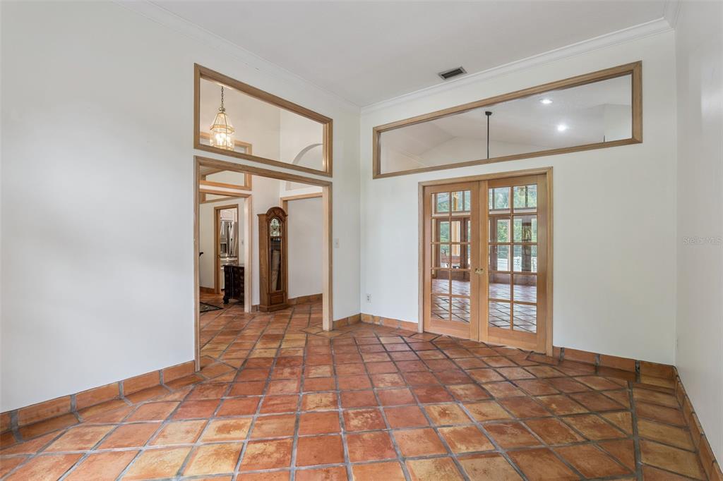 A room with terracotta tile flooring, French doors, and transom windows above the doorways — 381 CREEKSTONE COURT, LONGWOOD, FL