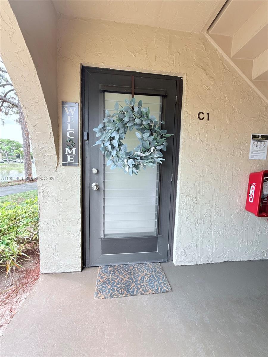 An exterior view of a residential unit entrance featuring a gray door with a wreath — 340 Pine Ridge Cir # 1, Green Acres FL 33463, GREEN ACRES, FL
