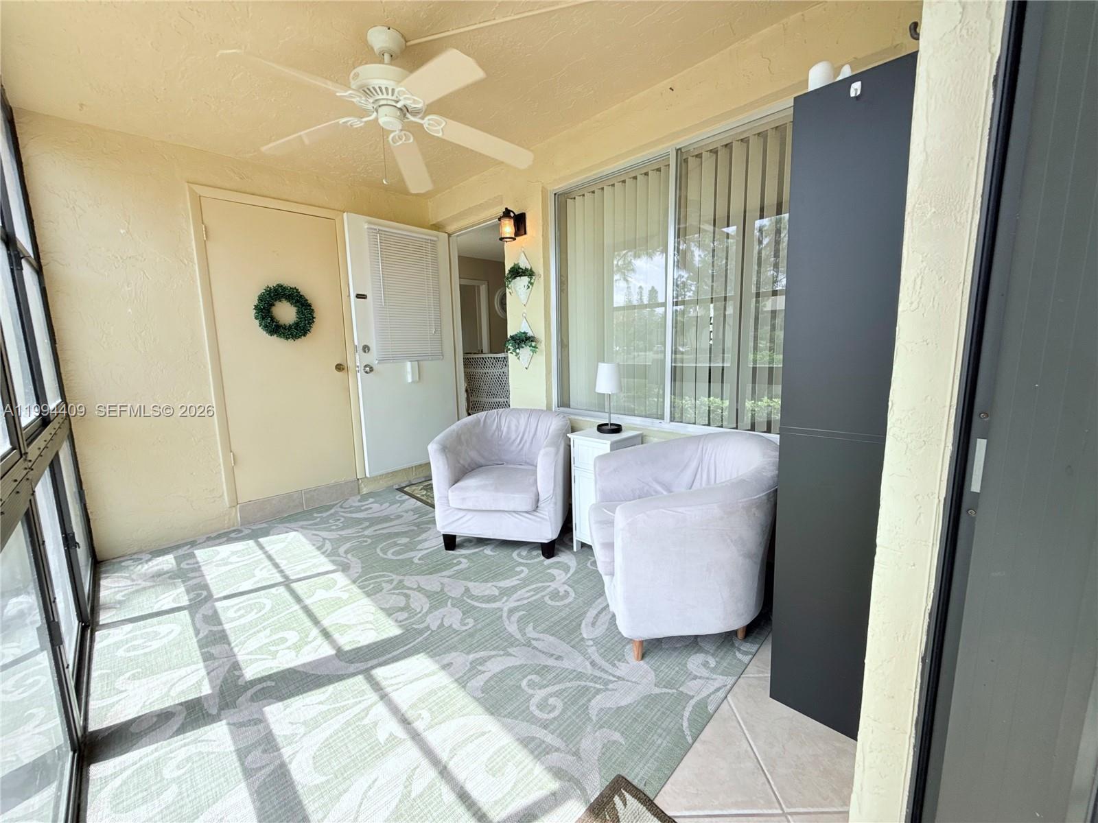 A sunroom features a ceiling fan, two light-colored armchairs, and a patterned area rug — 340 Pine Ridge Cir # 1, Green Acres FL 33463, GREEN ACRES, FL